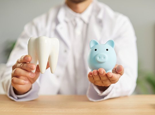 A dentist holding a piggy bank and a model tooth in his hands