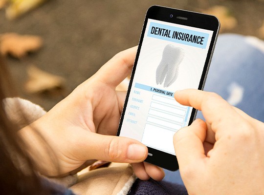 Patient looking at dental insurance form on phone outside