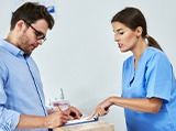 A man signing documents in a dental clinic