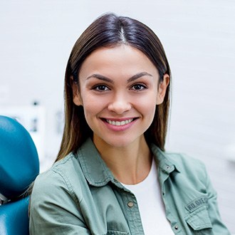 Smiling young woman in dental chair wearing green shirt