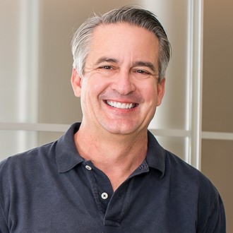 Older man smiling and wearing black polo shirt