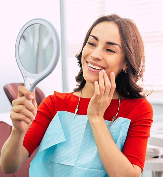 Woman in dental chair looking at smile in mirror