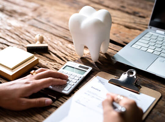 dental invoice calculator model tooth and laptop on desk