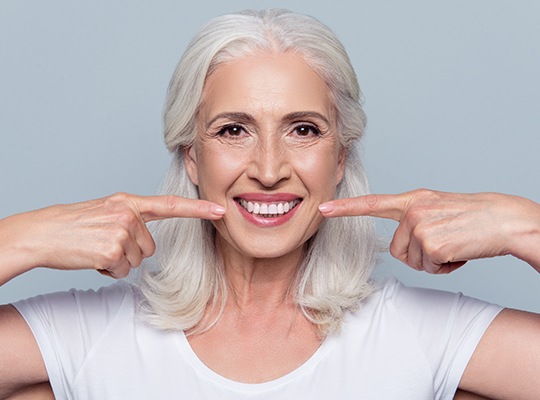 Older woman pointing to her smile