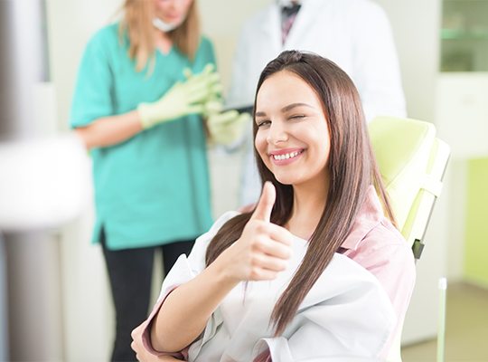 Woman in dental chair giving thumbs up