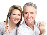 A middle-aged couple holding toothbrushes and preparing to clean their dental implants