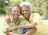 An older couple hugging and smiling while seated outside and enjoying the outdoors