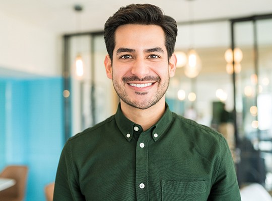 Man in green shirt smiling in an office
