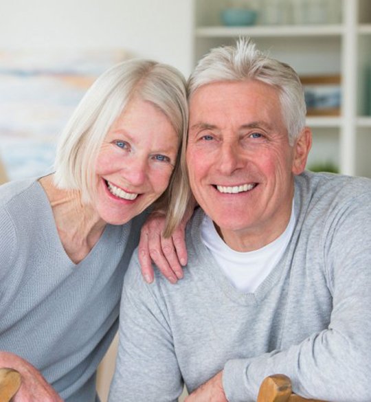 senior man and woman with implant dentures in Parma Heights showing off their smiles 