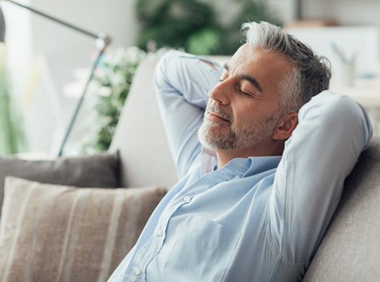 a man closing his eyes and resting on a couch