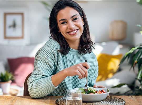 Woman smiling while eating lunch at home