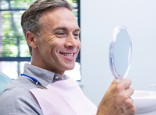 Older man looking at smile in mirror