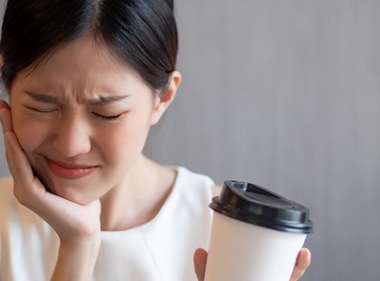 Woman experiencing tooth sensitivity from coffee
