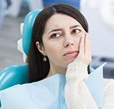 Woman in dental chair holding cheek