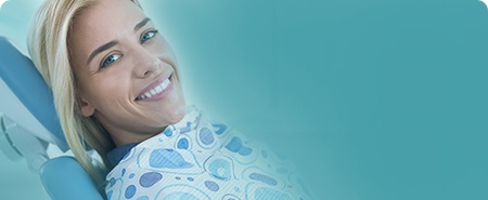 Woman sitting in dental chair smiling toward the camera