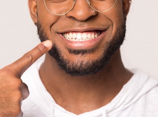 close-up of a man pointing to his smile