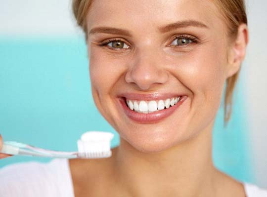 Woman with toothbrush smiling on blue background