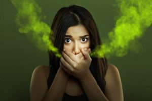 woman with bad breath covering mouth