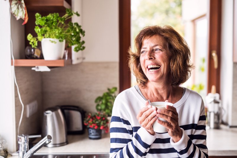 Senior woman smiling while drinking coffee in kitchen