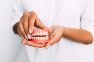 Woman holding ill-fitting dentures