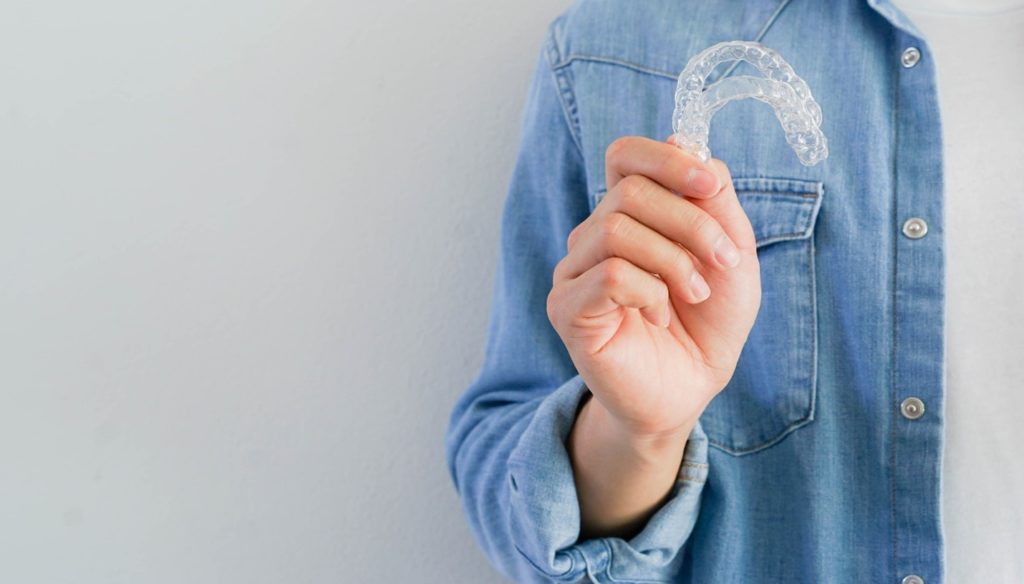 Person holding their Invisalign aligner.