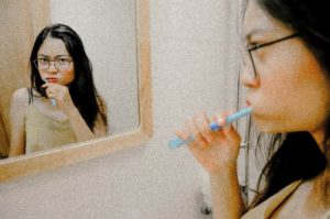 Woman looking in mirror and brushing her teeth