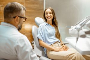 Woman in blue shirt and khakis consulting with dentist