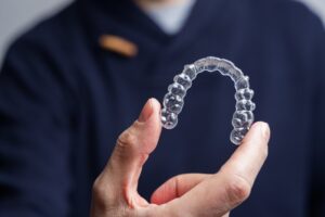 Dentist holding Invisalign in foreground. 