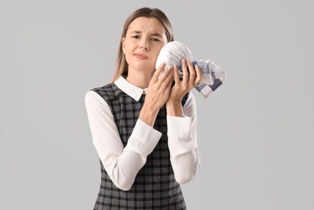 A woman holding an icepack to her face